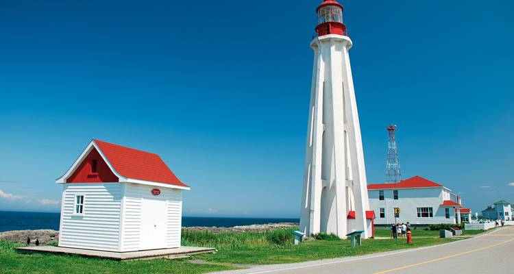 White lighthouse with red roof near the ocean.