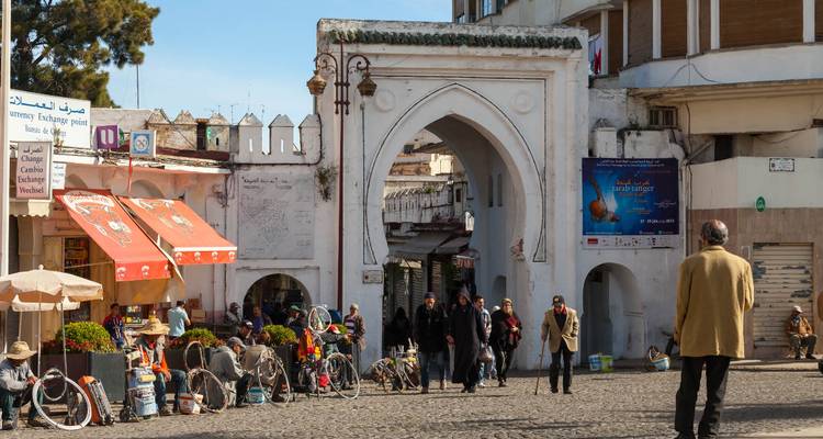 Eine belebte Marktstraße mit traditionellem Torbogen und Geschäften.
