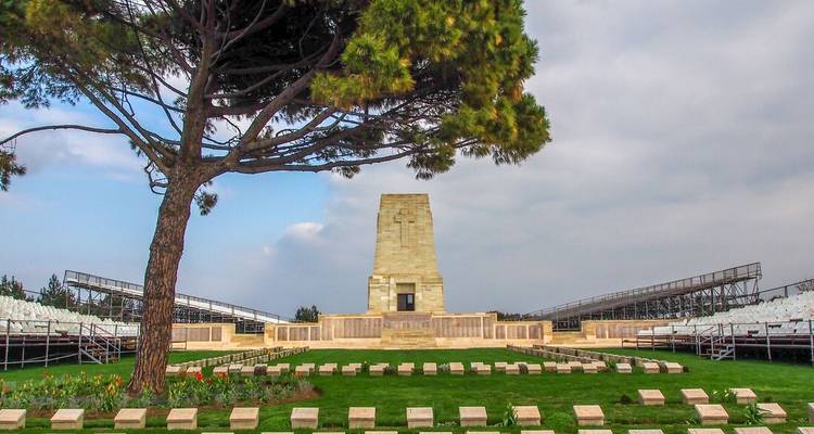 WWI memorial cemetery with grand stone obelisk and tiered seating under cloudy sky