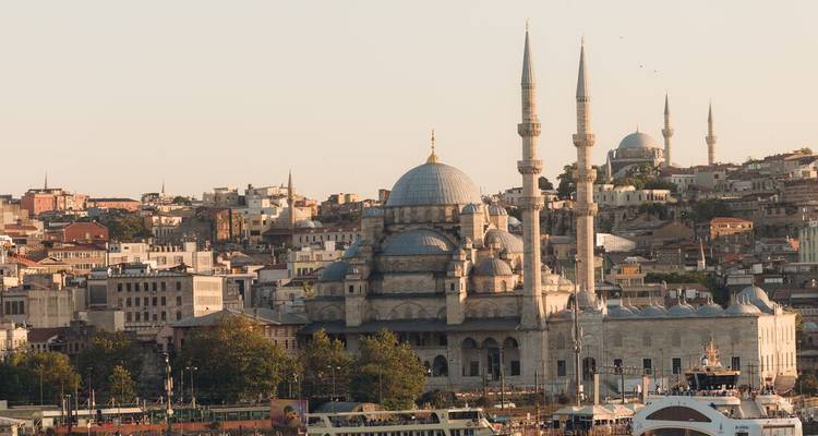 Golden hour panorama of Istanbul featuring the domes and minarets of the New Mosque rising above the waterfront skyline.