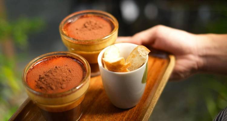 Deux verres de riche café vietnamien avec mousse de cacao servis sur un plateau en bois.