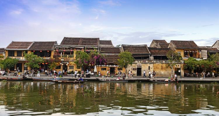 Les maisons-boutiques historiques au bord de la rivière de Hoi An se reflètent dans l'eau calme sous un ciel bleu du soir.