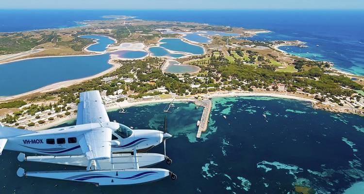 Weißes Wasserflugzeug schwebt über Rottnest Islands türkisfarbene Buchten, Seen und Küstenlinie.
