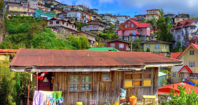 Colorido barrio en la ladera de casas de madera y concreto bajo un cielo brillante en Baguio.