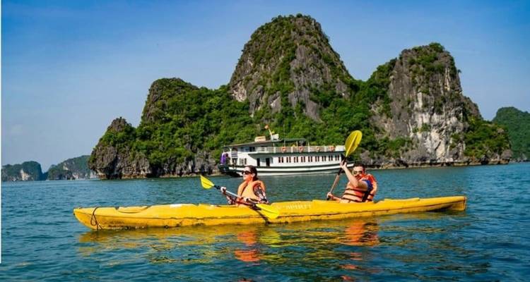 Personas navegando en kayak por aguas azules pintorescas con formaciones de piedra caliza.