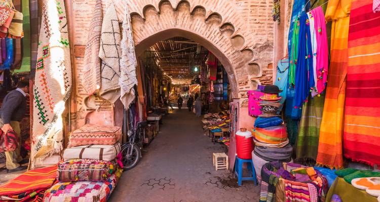 Colorful market street with textiles and archway entrance.