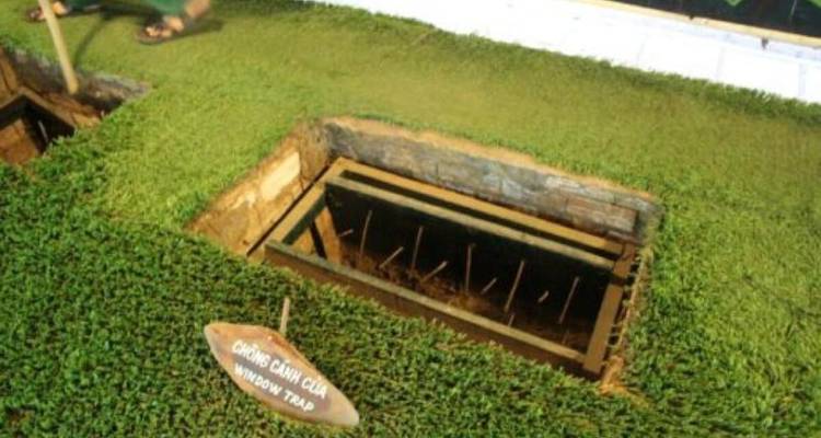 Trapdoor with spikes in a grassy area at a historical site.