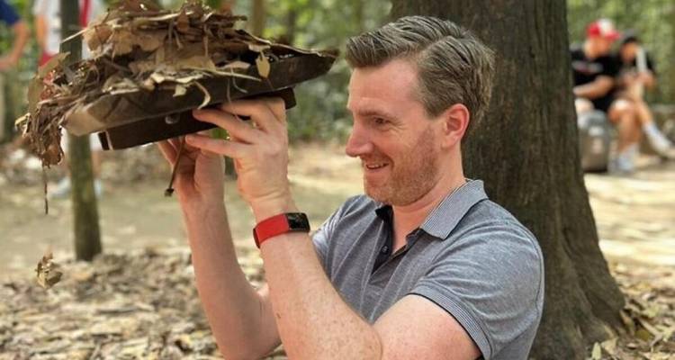 Man holding a leaf-covered lid, partially submerged in a tunnel.