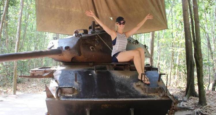 Woman sitting triumphantly on top of a vintage tank.