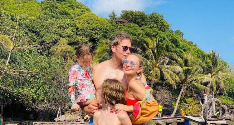 Famille posant ensemble devant un décor de plage tropicale.