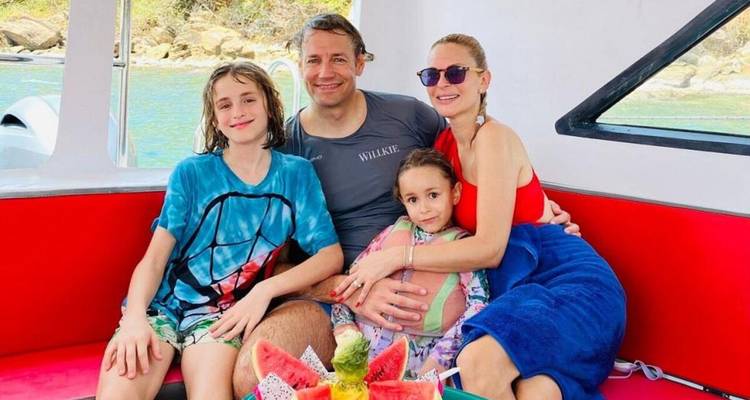 Famille assise ensemble profitant d'une promenade en bateau, avec un décor tropical.
