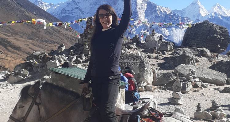 Person, die in einer bergigen Region auf einem Pferd reitet.