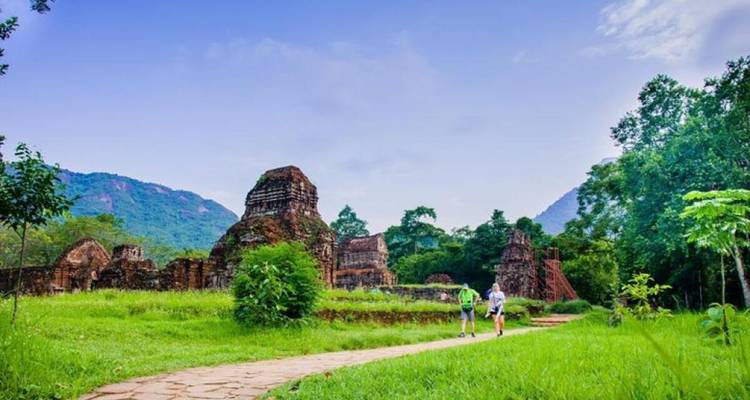 Des ruines verdoyantes luxuriantes avec deux personnes marchant sur un sentier.