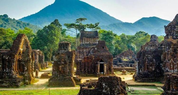 Ruines antiques avec une montagne en arrière-plan sous un ciel dégagé.