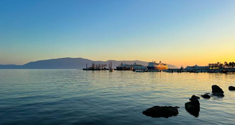 Serene havenschene met kalme zee, cruiseschepen en verre bergen in warm zonsondergangslicht
