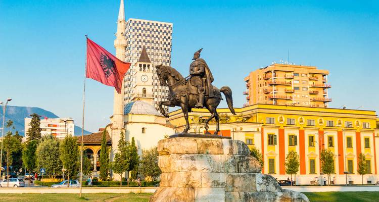 Ruiterstandbeeld van Skanderbeg met Albanese vlag, moskee en moderne gebouwen op het centrale plein van Tirana.
