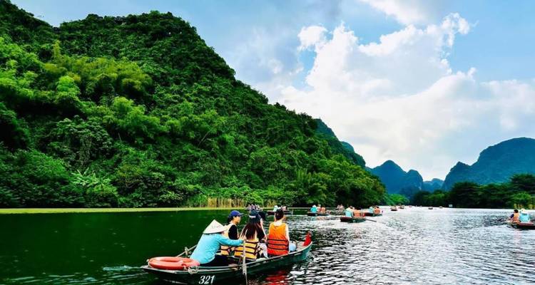 Toeristen die roeiboten roeien op een rivier met weelderige groene bergen.