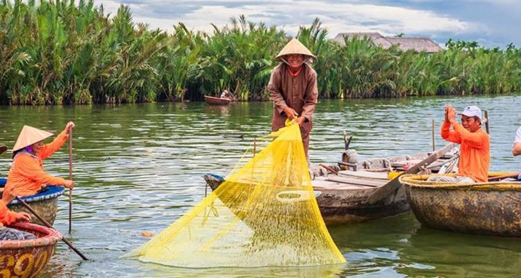 People fishing with a yellow net on boats in a lush river.