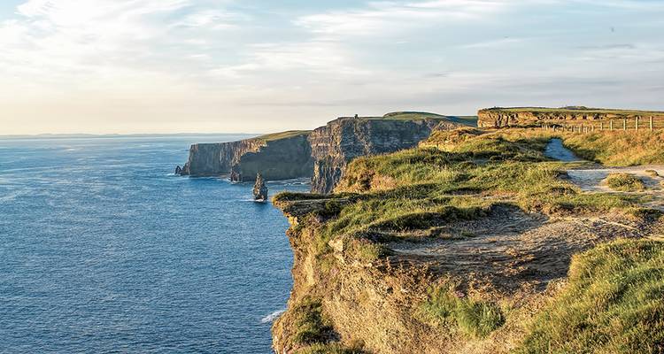 Acantilados verdes escarpados se precipitan hacia el Océano Atlántico a lo largo de los famosos Acantilados de Moher de Irlanda.