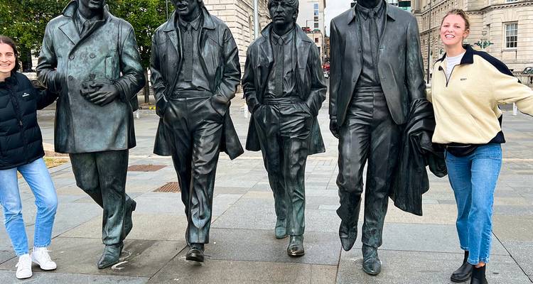Deux jeunes voyageurs posent avec les célèbres statues des Beatles sur une promenade de la ville.