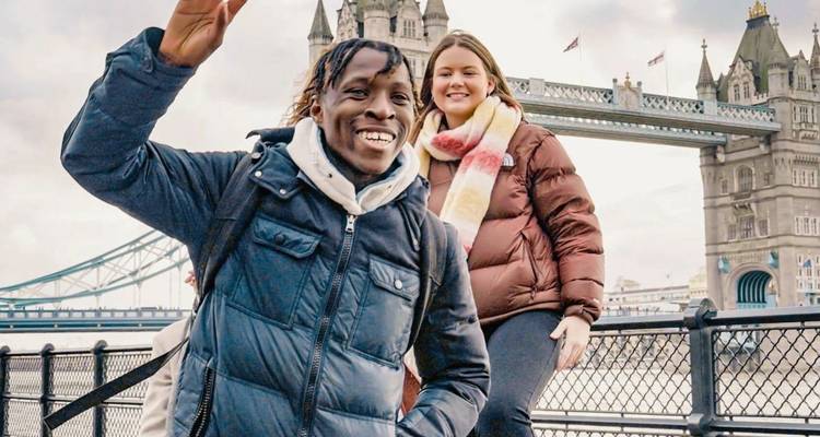 Los viajeros sonrientes posan frente al Puente de la Torre de Londres en un día fresco.