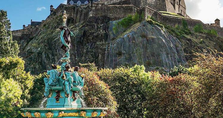 Ornate Ross Fountain framed by colourful foliage with Edinburgh Castle rising above rocky crags.