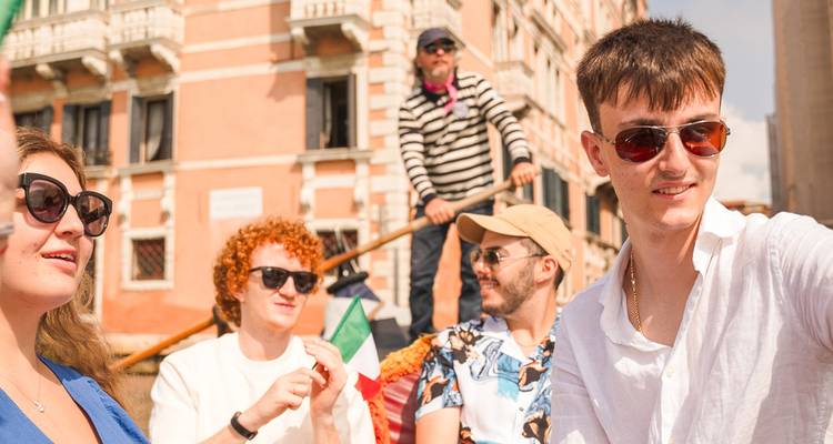 Un groupe profite d'une promenade en gondole à travers les canaux vénitiens ensoleillés, prenant des selfies à bord.