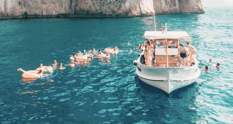 Das Ausflugsboot ankert vor steilen Klippen, während Dutzende von Badegästen das türkisfarbene Mittelmeer geniessen.