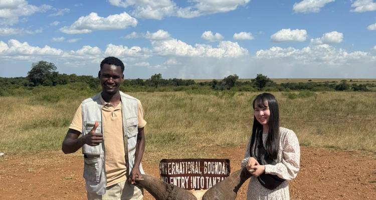 Deux personnes posant avec un crâne à cornes près d'une borne frontière.