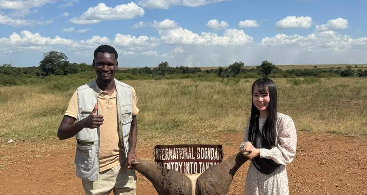 Deux personnes posant avec un crâne à cornes près d'une borne frontière.
