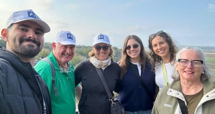 Groep mensen die samen poseren in de buitenlucht met een landschap op de achtergrond.