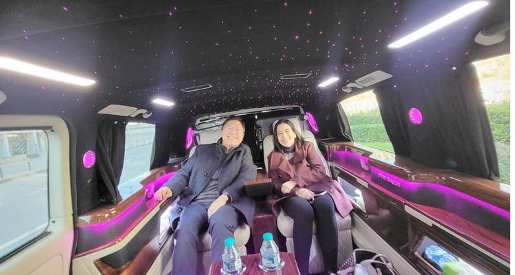 Stel glimlachend in een luxe busje verlicht door roze LED-plafondverlichting