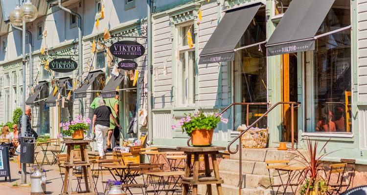 Street view of a cafe with people seated outdoors on a sunny day.
