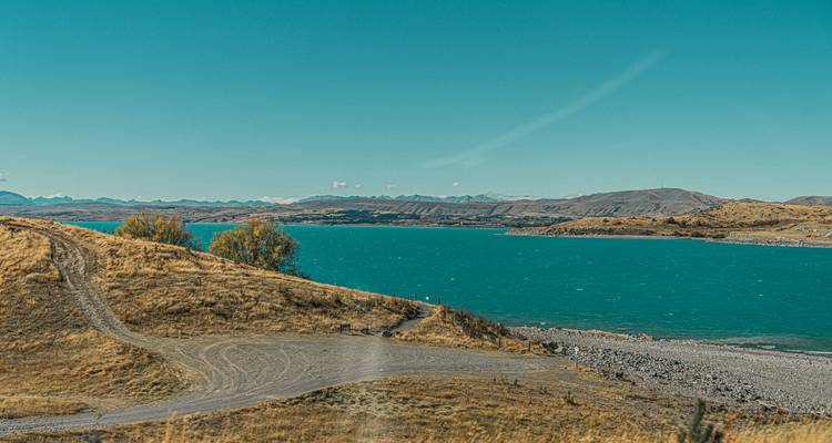 Malerische Landschaft mit einem See, Hügeln und einem klaren blauen Himmel.