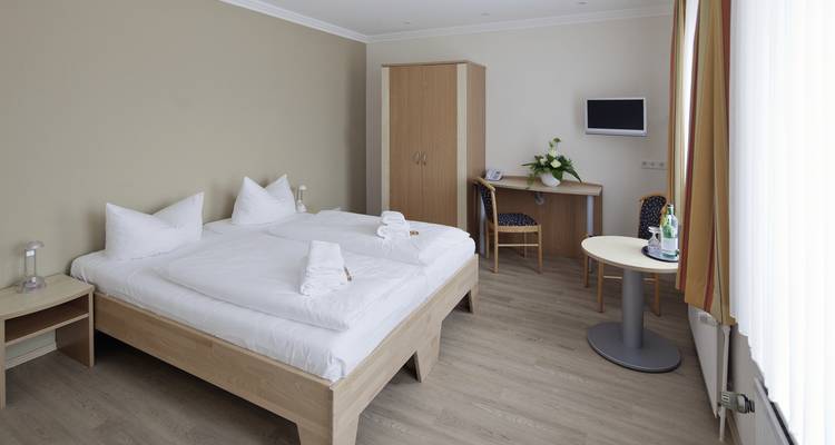 Chambre d'hôtel moderne et lumineuse avec un lit double.