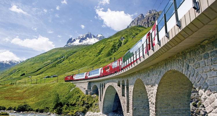 Train suisse circulant sur un viaduc avec vue sur la montagne.