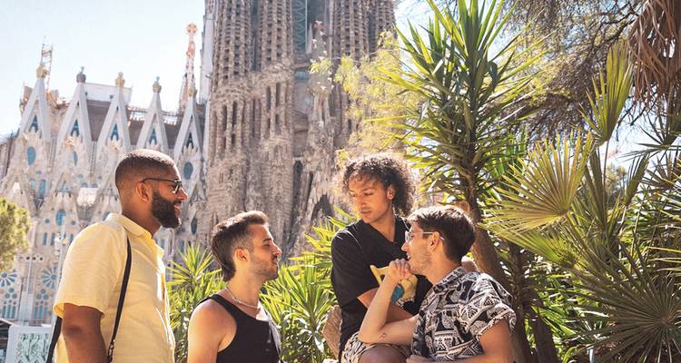 Des amis discutent parmi les palmiers avec la Sagrada Familia de Barcelone qui s'élève en arrière-plan par une journée ensoleillée