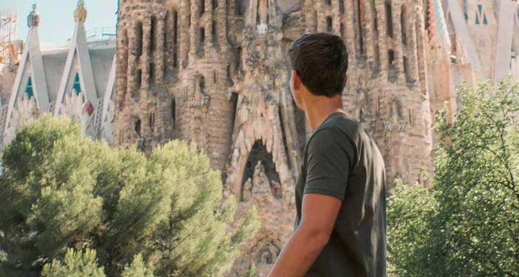 Un voyageur contemple la façade ornée de la basilique de la Sagrada Familia à Barcelone.