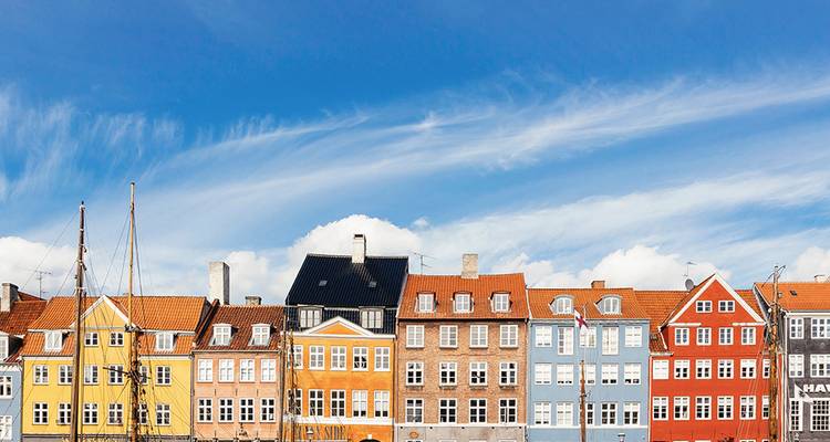 Rangée de bâtiments historiques colorés le long du port de Nyhavn à Copenhague sous un ciel bleu éclatant.
