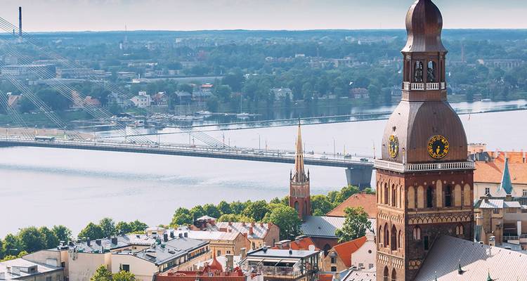 Vista panorámica de Riga con la torre del reloj de la catedral y el puente que cruza el río Daugava.