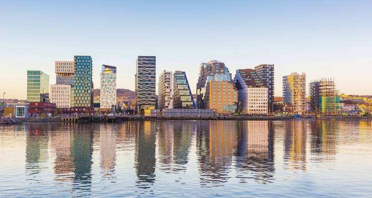 Modern skyline reflecting on the waterfront at dusk.