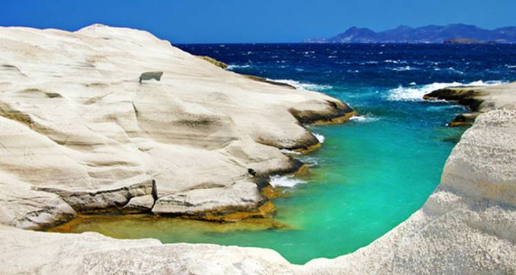 Petite baie turquoise éclatante encadrée par des formations de roches volcaniques blanches lisses sur l'île de Milos.