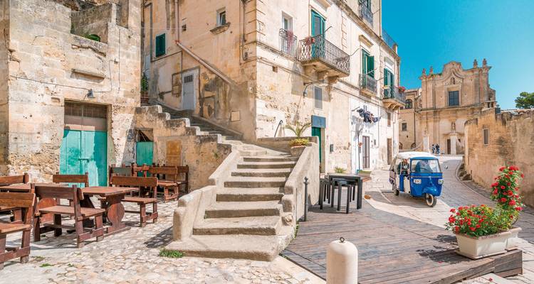 Malerische italienische Straßenszene mit historischer Architektur und einem kleinen Fahrzeug.