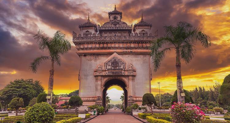 Monumentales Tor mit Gärten und Abendhimmel.