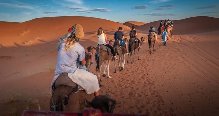 Gruppe von Menschen auf einer Kamelkarawanen-Reise durch die Wüste.
