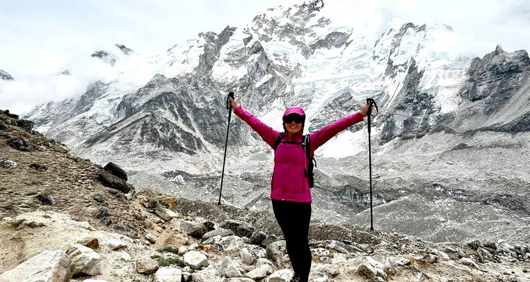 Wanderer posiert mit Trekkingstöcken vor Bergkulisse.