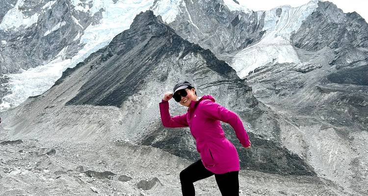 Person posiert verspielt vor zerklüfteter Berglandschaft.