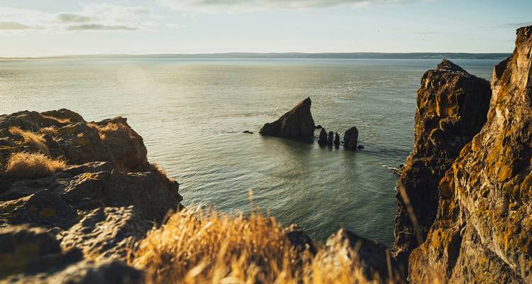 Costa escarpada con formaciones rocosas dramáticas al atardecer.
