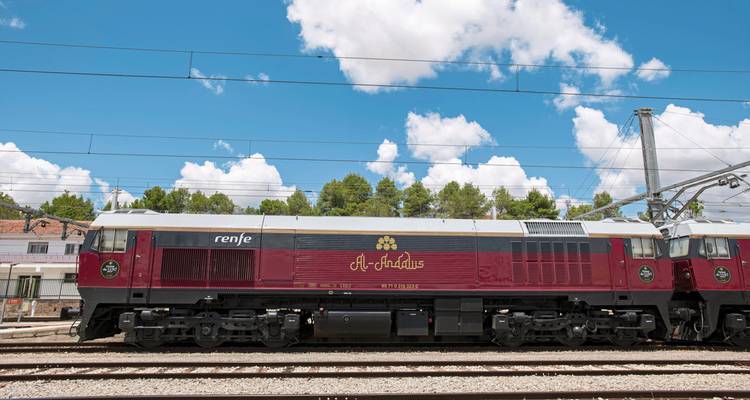 Luxe trein geparkeerd op een station, met een rood-witte locomotief