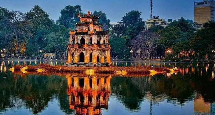 Une structure de temple illuminée sur une île dans un lac au crépuscule.